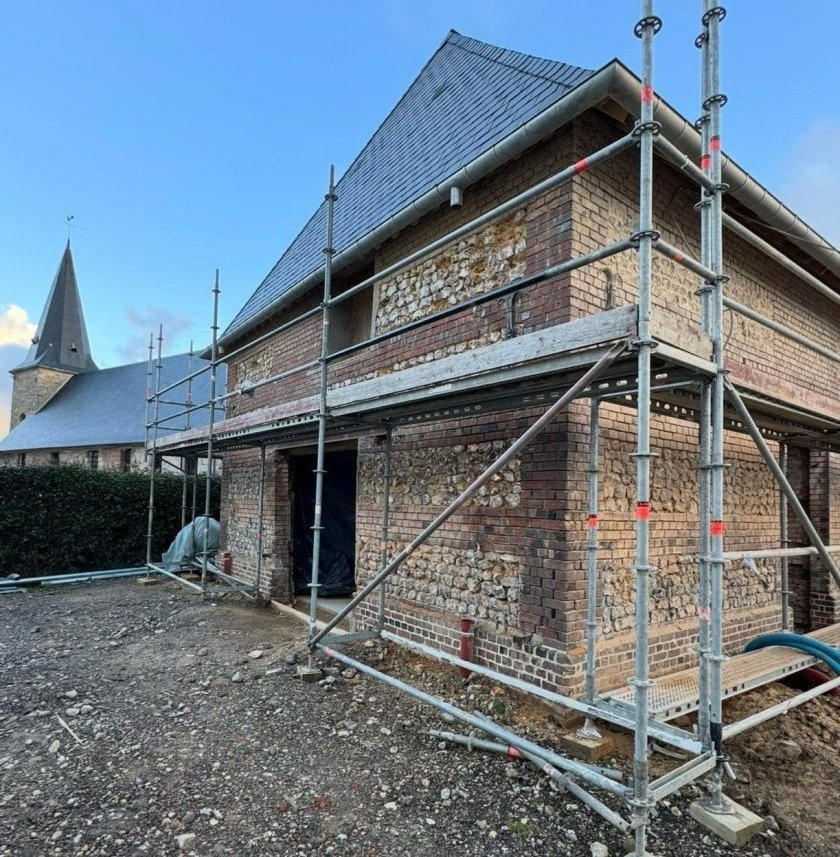 Artisan maçon réalisant un rejointoiement de façade en brique à Montivilliers